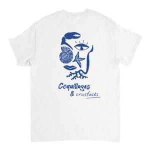 Peut inclure: T-shirt blanc avec un motif graphique bleu représentant un visage composé de coquillages et de crustacés. Le texte "Coquillages & crustacés" est imprimé en dessous.