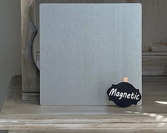 May include: A grey metal magnetic board with a black chalkboard sign that says "Magnetic" on a wooden shelf.