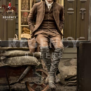 May include: A man wearing a brown jacket, waistcoat, and trousers sits on a wooden ledge. He is wearing tall brown boots and has a white cravat around his neck. The image is set against a backdrop of a wooden building and a pile of hessian sacks.