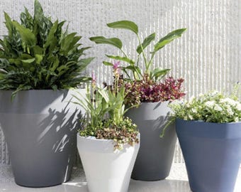 May include: Four large, modern planters in shades of gray, white, and blue, each filled with lush green plants and colorful flowers. The planters vary in size and shape, creating a visually appealing arrangement for outdoor or indoor decor.