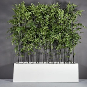 May include: A rectangular white planter box filled with artificial bamboo plants. The bamboo stalks are black, and the leaves are green. The planter is set against a gray background, creating a modern, minimalist aesthetic.