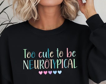 May include: Black sweatshirt with the text "Too cute to be neurotypical" in rainbow colors with five small pink, blue, and purple hearts below the text.
