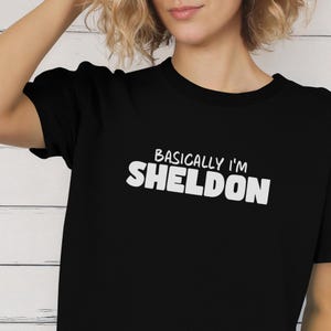 May include: Black t-shirt with white text that reads "Basically I'm Sheldon".