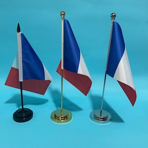 Peut inclure: Trois drapeaux de bureau miniatures arborant le motif de la République tchèque avec des sections horizontales et triangulaires bleues, blanches et rouges. Chaque drapeau est monté sur une tige verticale avec une base circulaire, en noir, or et argent.