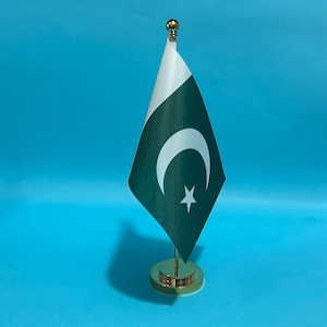 Peut inclure: Un petit drapeau de bureau du Pakistan composé d'un champ vert foncé avec une bande verticale blanche sur le côté de la hampe, un croissant de lune blanc et une étoile à cinq branches au centre, monté sur une tige et un socle en métal doré.