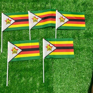 May include: Four small handheld flags of Zimbabwe, each featuring horizontal stripes of green, yellow, red, black, red, yellow, and green. A white triangle on the left side contains a red five-pointed star and a yellow Zimbabwe bird emblem.