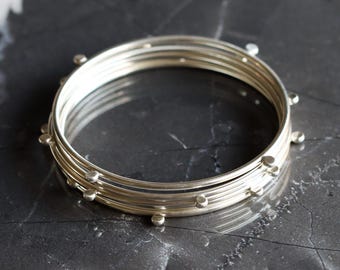 Modern silver stacking bangles, set of 5 silver bracelets with 4 silver balls to give an illusion of constant motion - "Compass Bangles"