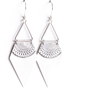 May include: A pair of silver earrings with a geometric design. Each earring features a triangular top, a textured fan-shaped middle section, and a diamond-shaped bottom. The earrings are suspended from a hook.