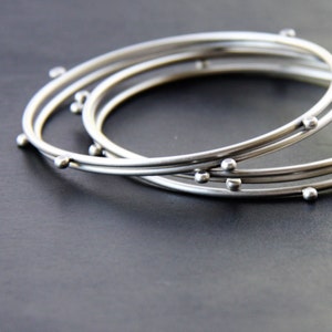 Modern silver stacking bangles, set of 5 silver bracelets with 4 silver balls to give an illusion of constant motion - "Compass Bangles"