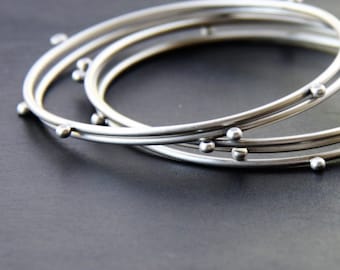 Modern silver stacking bangles, set of 5 silver bracelets with 4 silver balls to give an illusion of constant motion - "Compass Bangles"