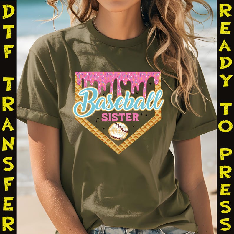 May include: A green t-shirt with a pink and blue baseball graphic that says "Baseball Sister". The graphic is a baseball diamond with a baseball in the middle and pink frosting dripping down the sides.
