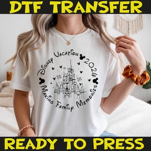K&ouml;nnte beinhalten: Wei&szlig;es T-Shirt mit einer schwarzen Grafik mit einem Schloss, Mickey-Mouse-Silhouetten und dem Text "Disney Vacation 2020 Making Family Memories". Die W&ouml;rter "DTF TRANSFER" und "READY TO PRESS" sind ebenfalls abgebildet.