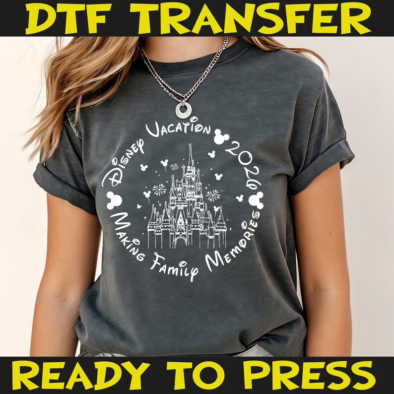 K&ouml;nnte beinhalten: Dunkelgraues T-Shirt mit einem wei&szlig;en Aufdruck eines Schlosses, Mickey Mouse-K&ouml;pfen und dem Schriftzug "Disney Vacation 2020 Making Family Memories". Das Shirt hat hochgekrempelte &Auml;rmel und die gelben Schriftz&uuml;ge "DTF TRANSFER" und "READY TO PRESS".