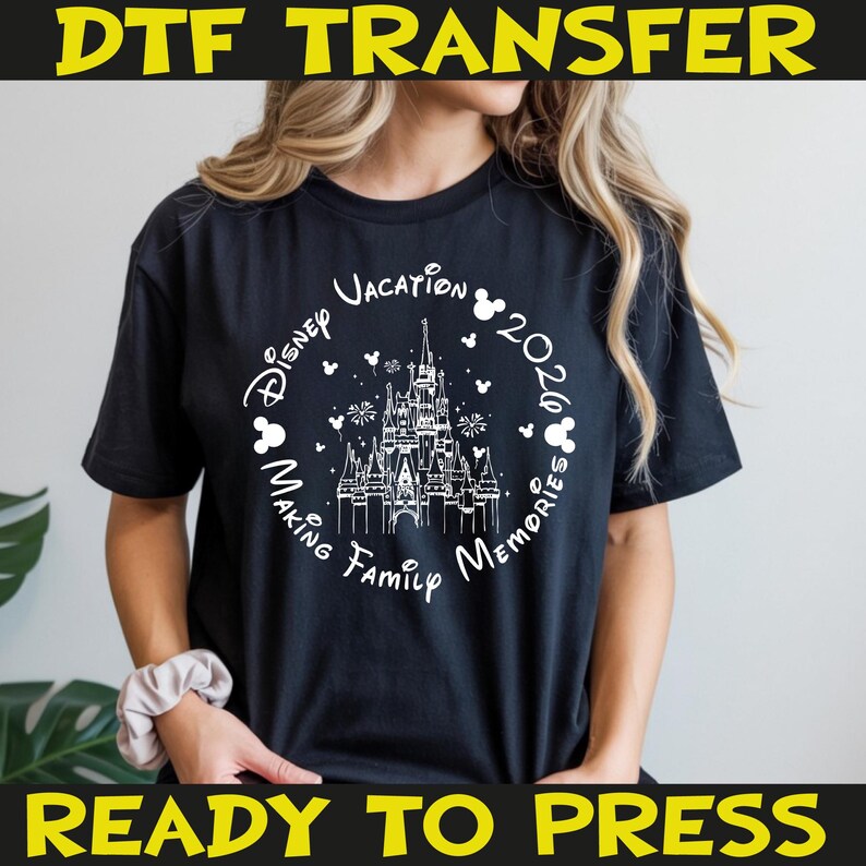 K&ouml;nnte beinhalten: Schwarzes T-Shirt mit wei&szlig;er Grafik, die ein Schloss, Mickey Mouse-Silhouetten und den Text "Disney Vacation 2026 Making Family Memories" zeigt. Die W&ouml;rter "DTF TRANSFER" und "READY TO PRESS" sind gelb gedruckt.