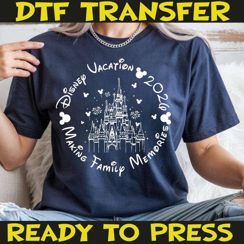 K&ouml;nnte beinhalten: Marineblaues T-Shirt mit wei&szlig;er Grafik mit einem Schloss, Mickey Mouse-Silhouetten und dem Text "Disney Vacation 2026 Making Family Memories". Die W&ouml;rter "DTF TRANSFER" und "READY TO PRESS" sind ebenfalls sichtbar.