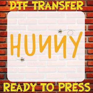 May include: A DTF transfer design featuring the word "HUNNY" in yellow, with two cartoon bees. The design is on a white background with a brick wall texture. The text "DTF TRANSFER" and "READY TO PRESS" are in yellow.