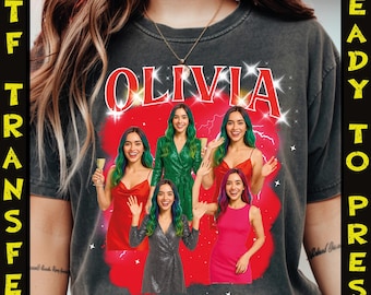 May include: Dark gray t-shirt with the name "OLIVIA" in red, surrounded by starbursts. The shirt features a graphic of five women in various dresses and hairstyles, set against a red backdrop. The words "DTF TRANSFER" and "READY TO PRESS" are printed vertically on the sides.
