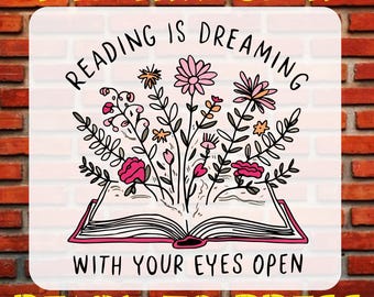 May include: A pink and white iron-on transfer design featuring an open book with flowers growing out of it. The text reads "Reading is dreaming with your eyes open".