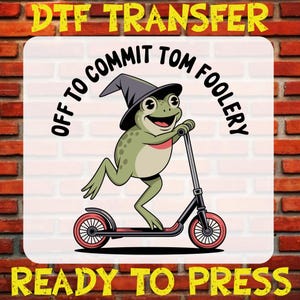 May include: DTF transfer design featuring a cartoon frog wearing a witch hat and riding a scooter. The frog is green with a red collar. The text reads "OFF TO COMMIT TOM FOOLERY" and "READY TO PRESS" in yellow.