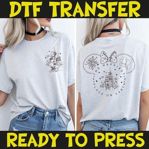 May include: Light gray t-shirt with a black graphic on the front and back. The front graphic features a cartoon character and a castle. The back graphic says "The Happiest Place on Earth" with a castle and fireworks. The text "DTF TRANSFER" and "READY TO PRESS" are at the top and bottom.