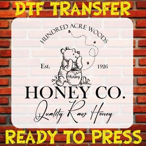 May include: DTF transfer featuring a black and white illustration of Winnie the Pooh with a honey pot. The design includes the text "Hundred Acre Woods," "Honey Co.," and "Quality Raw Honey." The words "DTF TRANSFER" and "READY TO PRESS" are also present.