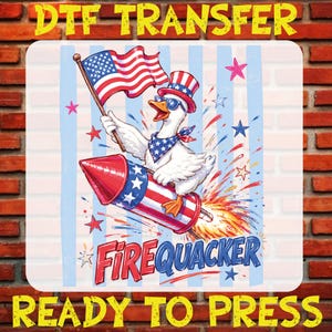 May include: A DTF transfer sheet featuring a white duck wearing a patriotic top hat, sunglasses, and a star-patterned bandana. The duck holds an American flag while riding a red, white, and blue firework. Text reads DTF TRANSFER and FIREQUACKER.