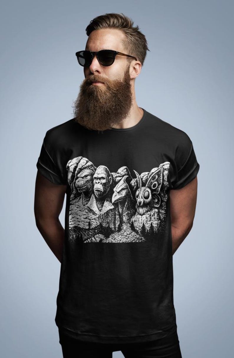 Puede incluir: Camiseta negra con un gr&aacute;fico en blanco y negro que representa cuatro criaturas, incluyendo una tortuga, un simio, un p&aacute;jaro y una polilla, talladas en una monta&ntilde;a. La camiseta la lleva una persona con barba y gafas de sol.