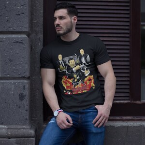 Peut inclure: Un t-shirt noir avec un imprim&eacute; graphique de quatre hommes en costume. Le graphique comprend le texte "Goodfellas" et "Midnight Hour".