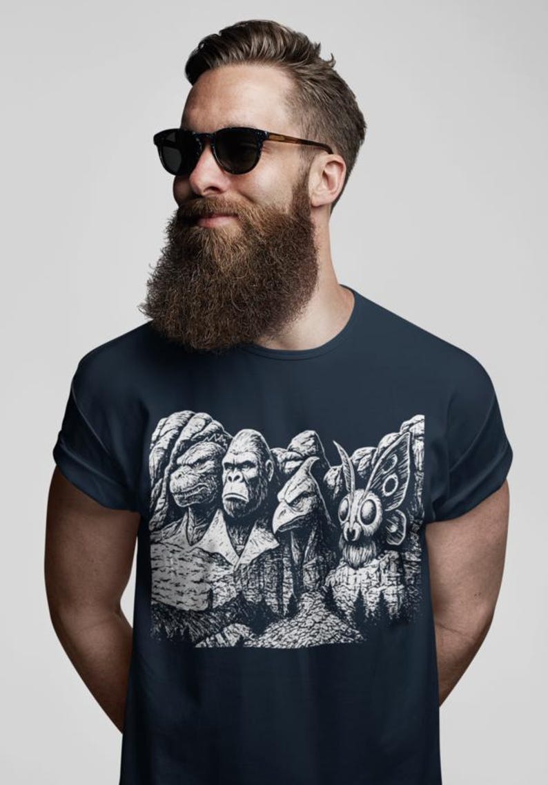 Puede incluir: Camiseta azul marino con un dise&ntilde;o gr&aacute;fico en blanco y negro de cuatro criaturas talladas en una monta&ntilde;a. Las criaturas son una tortuga, un gorila, un p&aacute;jaro y una polilla. Cuello redondo.