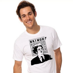 May include: White t-shirt with a black and white graphic of a person with a large afro and glasses. The graphic says "BRINGO!" and features a bingo card with numbers.