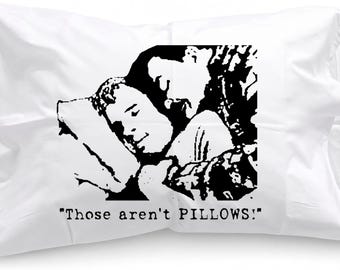 May include: A white rectangular pillowcase featuring a black graphic print of two people lying down, with the text "Those aren't PILLOWS!" printed in a typewriter-style font underneath the illustration. The pillowcase has a standard rectangular shape.