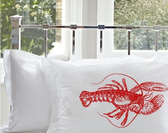 May include: A white pillowcase featuring a detailed, vibrant red illustration of a lobster centered on the fabric. The design showcases the crustacean in a classic, etched style with visible texture and shading, set against a plain white background.