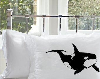 May include: A white pillowcase featuring a black and white graphic illustration of an orca whale centred on the fabric. The orca is depicted in a swimming position with its dorsal fin, tail, and pectoral flipper clearly visible in profile.