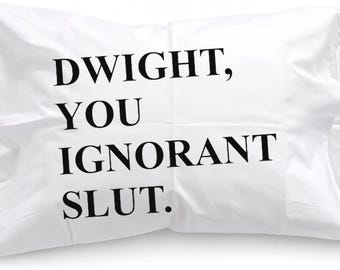 May include: A rectangular white pillowcase featuring the black printed text DWIGHT, YOU IGNORANT SLUT. The fabric is smooth and white, with the bold, sans-serif lettering centered on the front surface of the pillowcase in a clear, readable font.