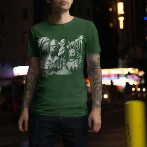 Puede incluir: Camiseta verde con un gr&aacute;fico blanco de criaturas estilizadas, incluyendo un gorila, un conejo y una polilla. La camiseta est&aacute; hecha de un material suave y es adecuada para ropa casual.