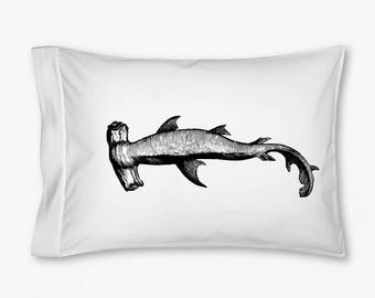 May include: A rectangular white pillowcase featuring a detailed black and white ink-style illustration of a hammerhead shark centered on the fabric. The shark is depicted in profile, showcasing its distinct wide head, fins, and curved tail.