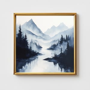 Op de afbeelding: Een ingelijste aquarel van een berglandschap in tinten blauw en wit. Het kunstwerk toont een serene scène met bergen, bomen en een reflecterend water. De schildering is ingelijst in een gouden lijst.