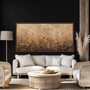 May include: A framed canvas art piece depicting a field of wildflowers in shades of brown, orange, and white. The artwork is displayed above a white sofa with matching pillows. The room also features a woven coffee table and chairs.