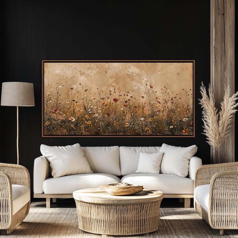 May include: A framed canvas art piece depicting a field of wildflowers in shades of brown, orange, and white. The artwork is displayed above a white sofa with matching pillows. The room also features a woven coffee table and chairs.