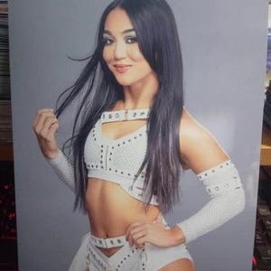 Könnte beinhalten: Eine Frau trägt ein weißes Crop-Top mit schwarzen Akzenten und dazu passende weiße Shorts mit schwarzen Akzenten. Sie hat langes schwarzes Haar und posiert mit der Hand auf der Hüfte.