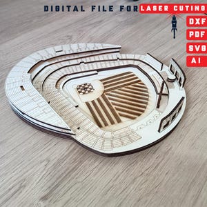 Könnte beinhalten: Ein lasergeschnittenes Holzstadionmodell mit detaillierten Merkmalen. Das Modell zeigt Tribünen, ein Spielfeld und architektonische Elemente. Der Text "DIGITAL FILE FOR LASER CUTING" ist oben. Datei-Typ-Symbole: DXF, PDF, SVG und AI.