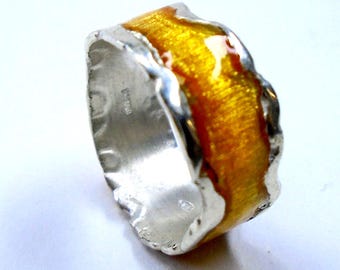 May include: A silver ring with a yellow and orange enamel band. The band has a textured, wavy design.