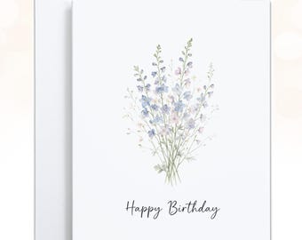 May include: A white greeting card featuring a watercolor illustration of a bouquet of light blue and soft pink delphinium flowers. The text Happy Birthday is printed in a simple black script font centered below the floral arrangement.