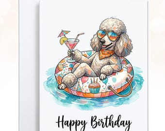May include: A white greeting card featuring a cartoon poodle wearing sunglasses and an orange bandana, lounging in a colorful patterned pool float in blue water. The poodle holds a cocktail with a small umbrella. The text Happy Birthday is below.