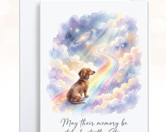 May include: A white greeting card featuring a watercolor illustration of a brown dachshund sitting on a rainbow path leading into a starry, cloud-filled sky. Below the illustration, the text reads: May their memory be etched into the Stars.