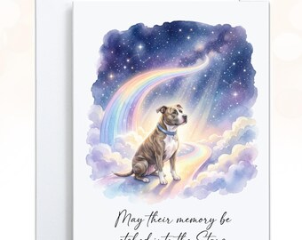 May include: A white greeting card featuring a watercolor illustration of a brown and white dog sitting on a rainbow path amidst clouds and a starry night sky. The text "May their memory be etched into the Stars" is printed in black script below the illustration.