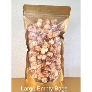 May include: A gold and clear plastic bag filled with caramel popcorn. The bag has a zipper closure and is labeled "Large Empty Bags".