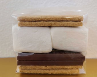 May include: A clear plastic bag filled with the ingredients for a s'more: graham crackers, marshmallows, and chocolate bars. The bag is labeled "Empty S'mores Bags".