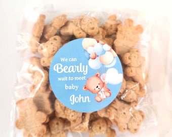 May include: A clear plastic bag filled with bear-shaped cookies. A blue and white sticker with the text "We can Bearly wait to meet baby John" is attached to the bag.