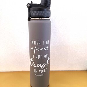 May include: A grey insulated water bottle with a black lid. The bottle has white text that reads "When I am afraid, I put my trust in you." Psalm 56:3.